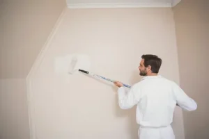 A Man paint in wall with brush low cost painting Services